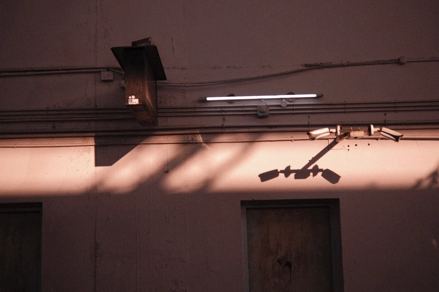 Security cameras casting angular shadows across a sunlit wall