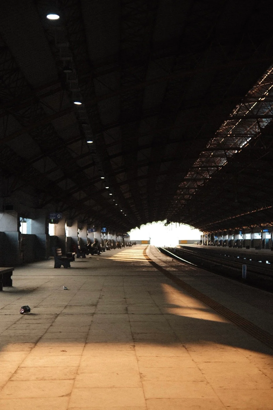 An empty railway platform leading toward a bright opening