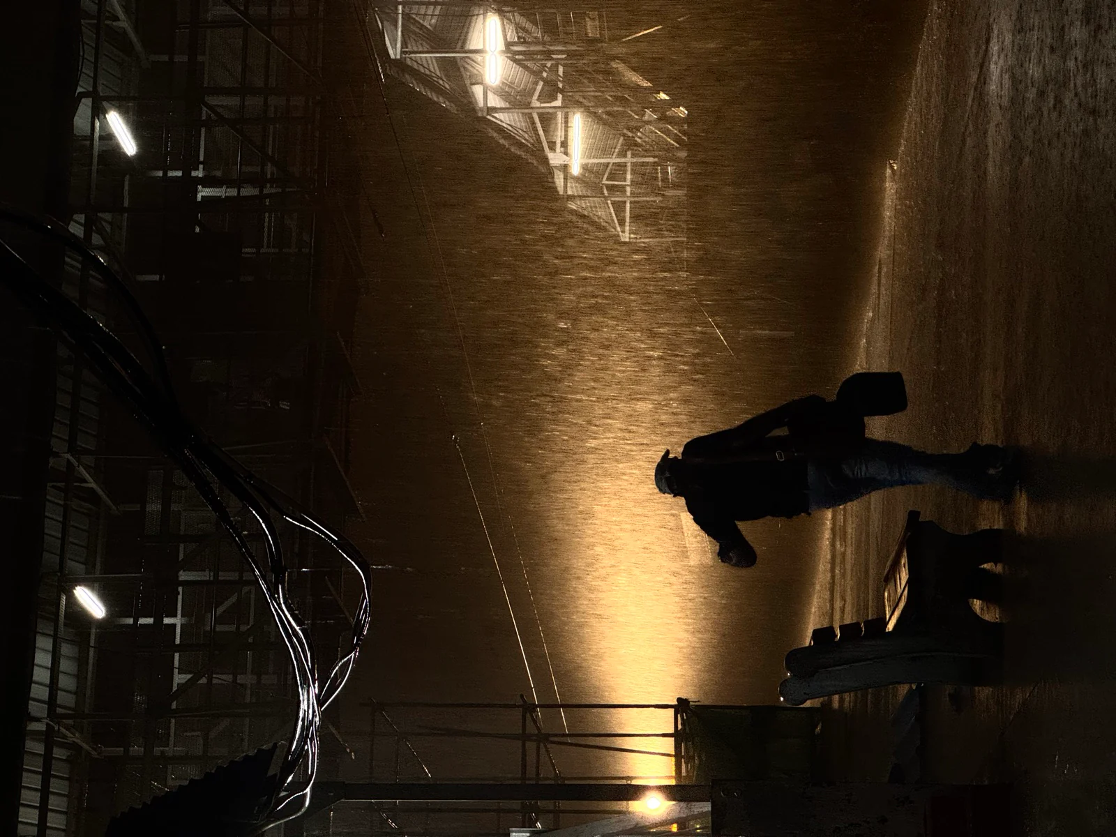 A traveller walking through heavy rain on a railway platform